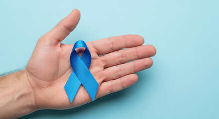 Male hand holding blue awareness ribbon on pastel background symbolizing support, hope and health disease prevention campaign