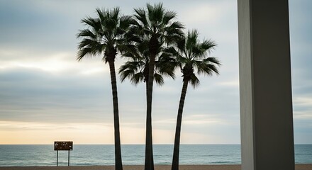 Three silhouetted palm trees stand on a quiet sandy beach against a calm ocean and cloudy sky at dusk, with a modern architectural column framing the serene view