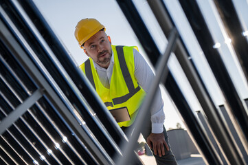 Male engineer inspecting solar panels with tablet outdoors