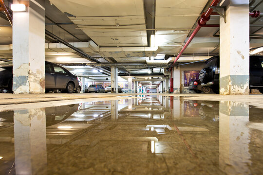 Underground parking garage in Moscow, Russia, with a large puddle on the floor.