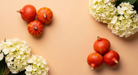 Arrangement of orange pumpkin and white hydrangea on beige background, symbolizing autumn, harvest, and seasonal decoration, with space for text.