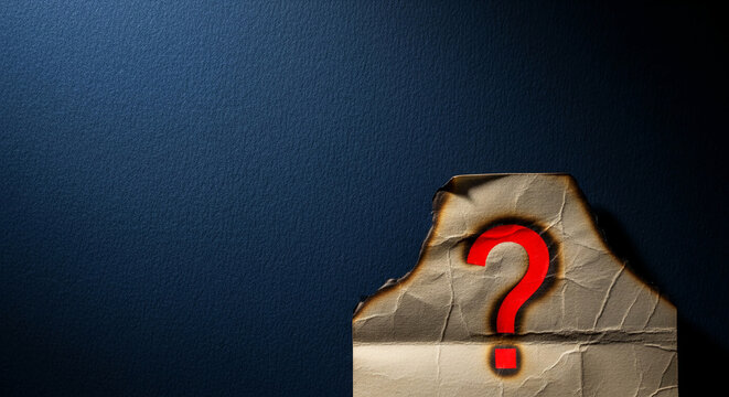 Burnt paper fragment with red question mark on textured dark blue surface, suggesting mystery, unknown, seeking information, or needing a solution
