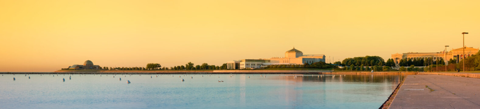 Chicago lake front and Museum Campus at sunset, a glow in thy sky, large public buildings on the shore, the Adler Planetarium, The Shedd Aquarium and the Field Natural History Museum. 