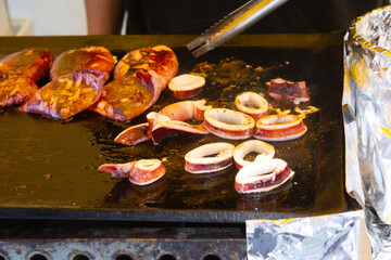 Close-up view of fresh squid being cooked at a Japanese street food market, with steam rising and a vendor preparing the dish. 
