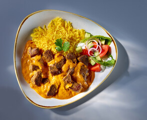 Indische Hauptspeise mit Curcumareis und RInd,  Topshot, gelber Reis, salat, Beilage, blauer...