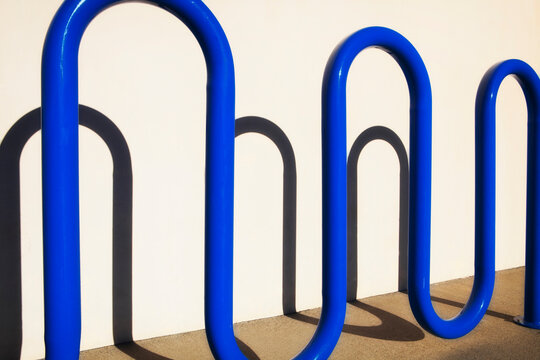Blue curved metal bike rack throwing a shadow on the wall in Redmond, California