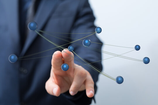 Close-up of a businessman's hand touching a network of digital spheres, symbolizing connection, technology, and
