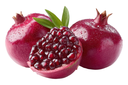 Fresh ripe pomegranates with opened fruit revealing juicy seeds and vibrant red color, decorative whole fruits and leaf accents on a white background