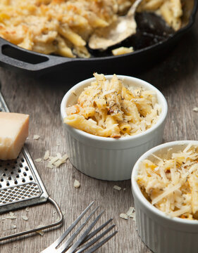 High angle close up of two ramekins and a dish with mac and cheese, cheese sauce and macaroni.