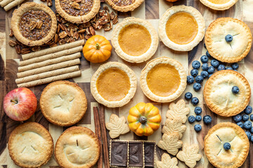 Seasonal dessert spread featuring various pies, fruits, and spices arranged on a wooden table for fall celebrations