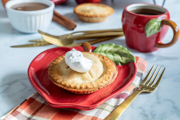 Delicious mini apple pie on a colorful plate with coffee and spices nearby during a cozy gathering