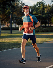 Senior biegający w parku z słuchawkami na uszach