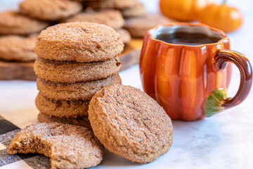 Delicious cookies stacked next to a warm pumpkin mug on a cozy autumn table setting