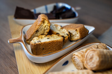 Close-up of delicious homemade biscotti with chocolate chips in a ceramic bowl. Part of a sweet assortment served on a wooden board. Inviting concept for a cozy coffee break.