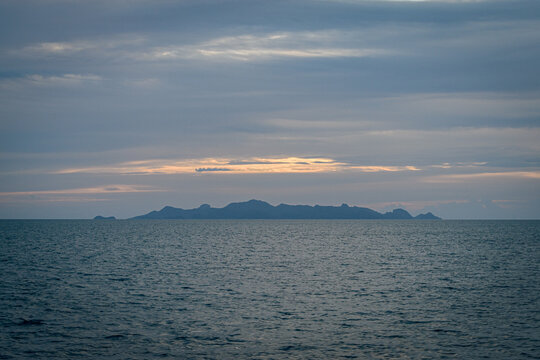 View across ocean with distant island at sunset.