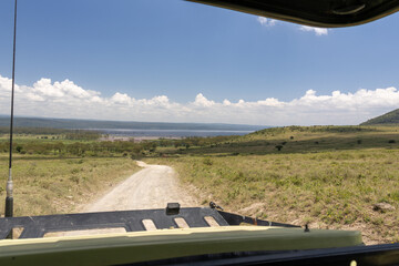 View from a safari vehicle over the dirt track toward Lake Nakuru and the open savanna in Kenya, East Africa