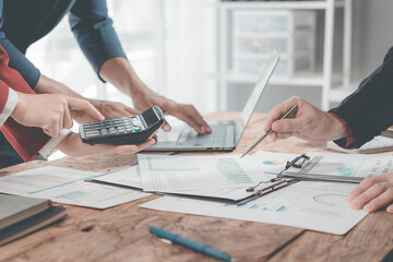 Business team analyzes financial data and charts together on digital tablets and laptops, and digital tablets to plan investment projects. Close-up.