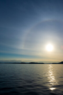 Rosario Strait, San Juan Islands, the view at sunset over the water to the islands beyond, a sundog halo of light around the sun.