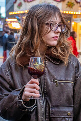 happy teenage girl drinks punch from a glass at a holiday fair.