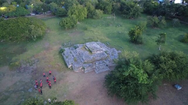 4K UHD drone rocket-style shot of Boy Scouts exploring an archaeological monument as the camera ascends and reveals the wider M&eacute;rida cityscape.