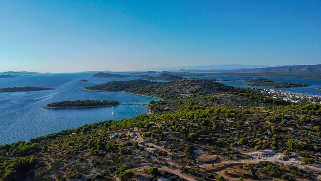 Small islands, vibrant green hills, and a picturesque town with a bustling marina on the horizon