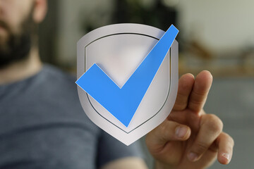 A man's hand interacting with a shield and checkmark symbol. Representing security, protection, and approval. Ideal for cybersecurity