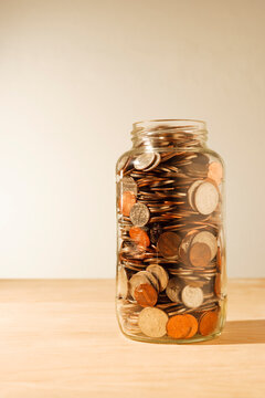 US coins collected in a glass jar, quarters, dollars, nickels and dimes. 