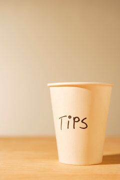 Tips cup, a white paper cup for gratuities on a table. 