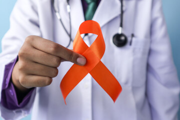 A doctor is holding a leukemia or kidney cancer ribbon on an isolated background