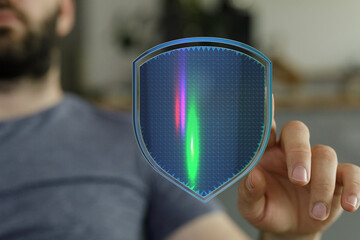 Man's hand pointing at a digital shield symbolizing cybersecurity, data protection, and online safety. The futuristic design suggests