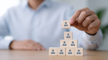 Focused businessman building team hierarchy with wooden block. Corporate leadership, management structure vital resource for business organization