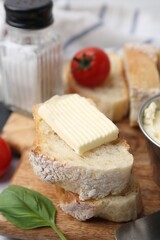 Slices of baguette with butter, basil and tomatoes on table, closeup