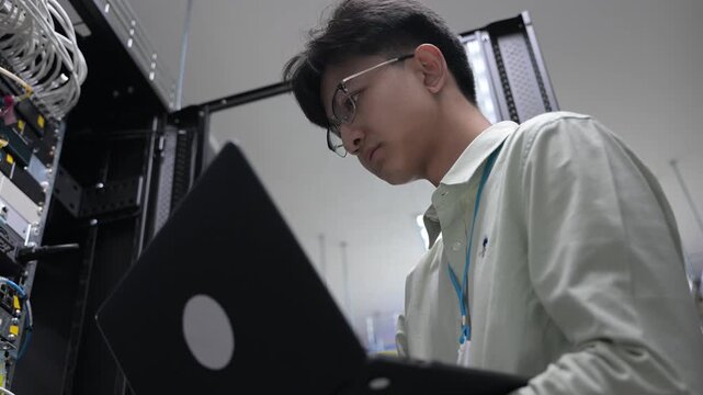 Computer engineer is setting up network in server room,Systems Maintenance Technician,Male engineer working in server room at modern data center - Powered by Adobe