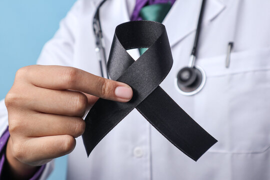 A doctor is holding a skin cancer ribbon on an isolated background