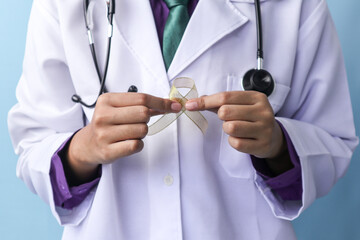 A doctor is holding a childhood cancer ribbon on an isolated background