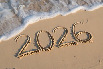 The year 2026 written in the sand on a beach with a wave coming in