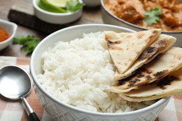 Delicious rice, lavash, chicken tikka masala and spoon on table, closeup