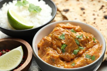 Delicious chicken tikka masala, cilantro, rice, lime and peppercorns on plate, closeup