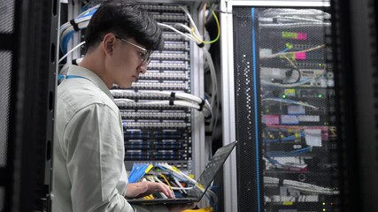 Computer engineer is setting up network in server room,Systems Maintenance Technician,Male engineer working in server room at modern data center - Powered by Adobe