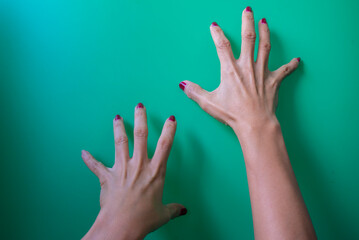 Female hands with pink manicure on a green background, close up