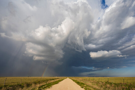 Back Side of a Supercell with a Rainbow above a road reaching the horizon. 