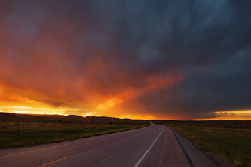 Sunset on WY Highway 59, the glow of the setting sun on the horizon, and storm clouds in the sky.