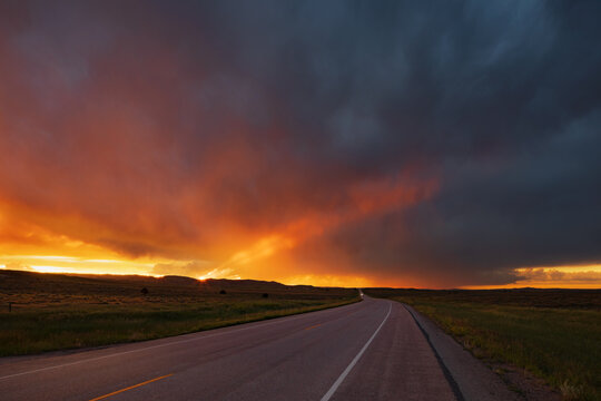 Sunset on WY Highway 59, the glow of the setting sun on the horizon, and storm clouds in the sky.