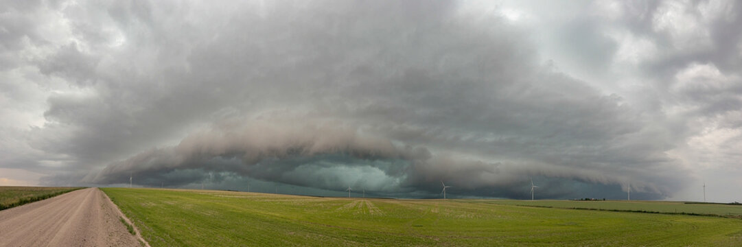 Storm with a  Mesocyclone or a Rotating Updraft, a cloud formation rising above a green field in a flat landscape.