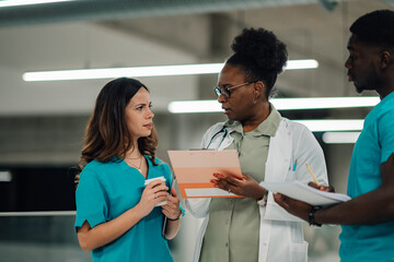 Diverse medical team discussing patient data in hospital corridor