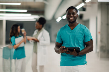 African american male nurse holding digital tablet smiling
