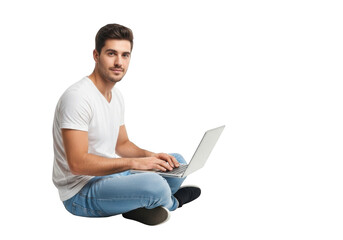 Young man sitting cross legged on the floor working on a laptop computer with a focused expression