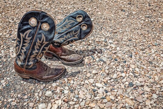 Worn Leather Cowboy Boots on Gravel Ground