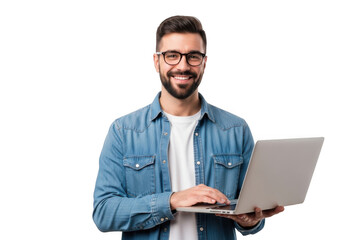 Smiling young man with beard and glasses wearing a denim shirt holds a laptop and types on the keyboard against a black background
