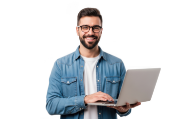Smiling young man with beard and glasses wearing a denim shirt holds a laptop and types on the keyboard against a black background